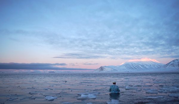 Artist wades into water, in Arctic Lanscape