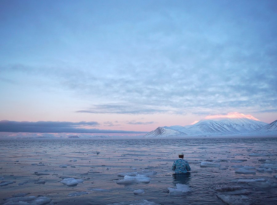 Artist wades into water, in Arctic Lanscape